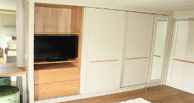 Fitted sliding door wardrobe in painted tulipwood and oak interior